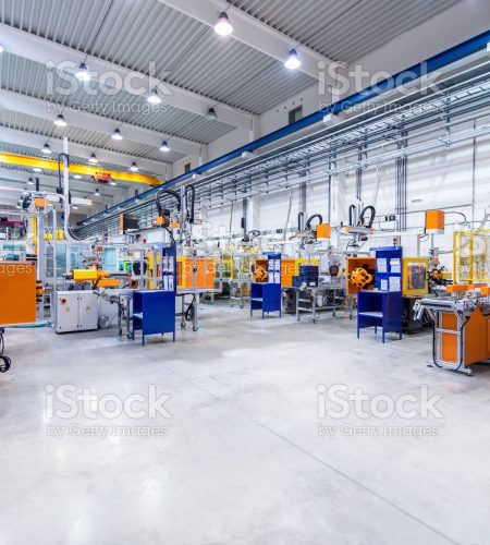 Horizontal image of huge new modern factory with robots and machines producing industrial plastic pieces and equipment. Wide angle view of futuristic machines standing on flooring and having the monopole of all work, taking the place of human work. There is not necessary use human hand. Wide angle, view, no people, space for copy.